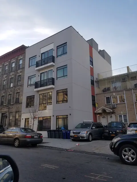 Street photograph of 264 Albany Avenue showing a light-colored facade, dark balcony railings, a warm-colored side accent and parked vehicles.